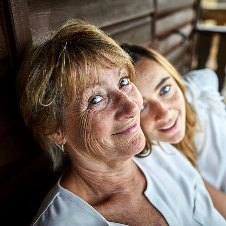 Mutter sitzt mit Tochter auf einer Holzbank | Doppelherz